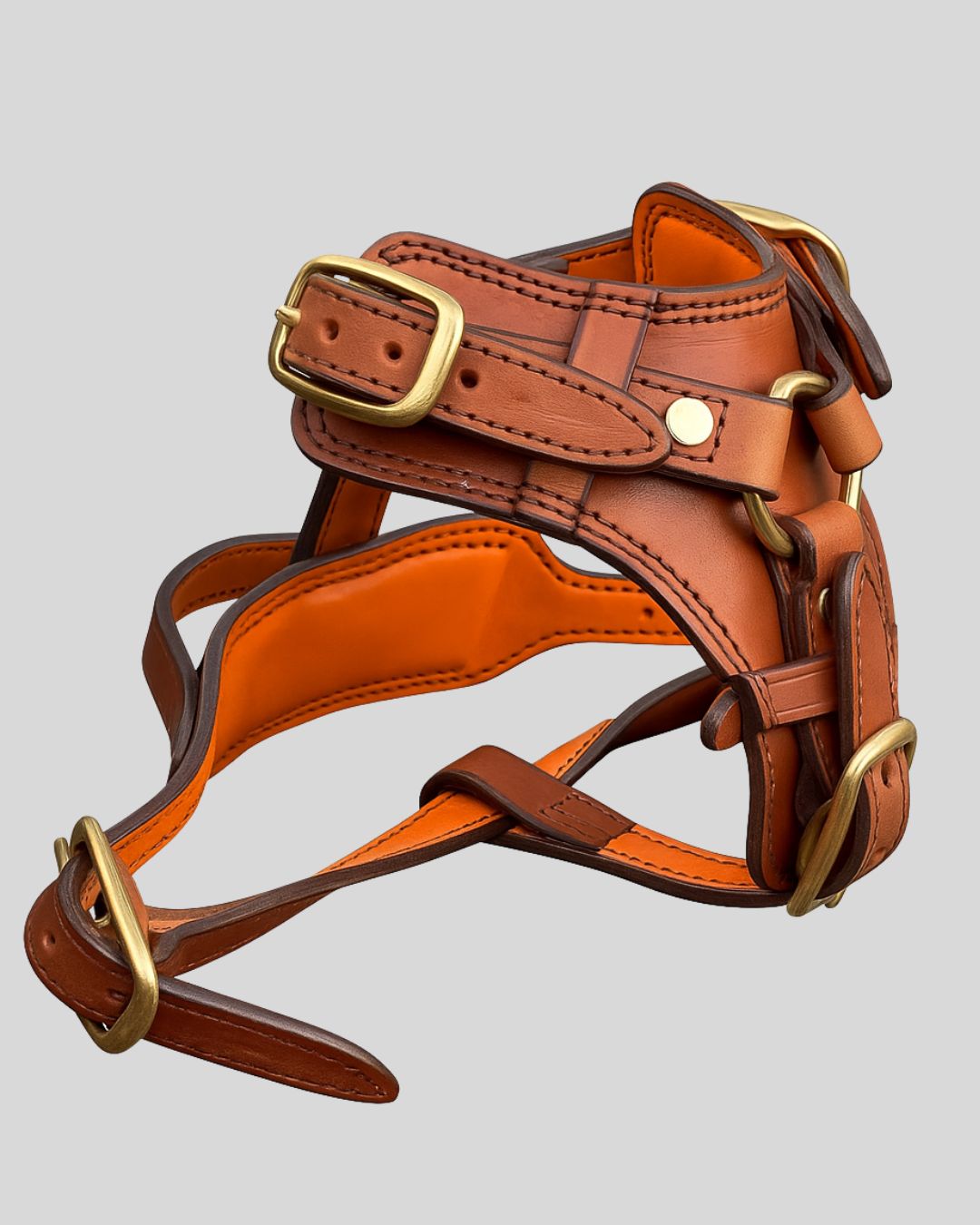 Side view of handcrafted tan leather dog harness with adjustable brass buckles and orange interior padding

